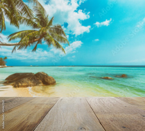 wooden table top with blur of beautiful tropical beach with coconut tree