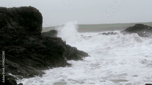 Storm Waves Crashing On Large Rocks As The Waves Hit Shore. Slow motion footage of large storm waves crashing on rocky cliffs. photo