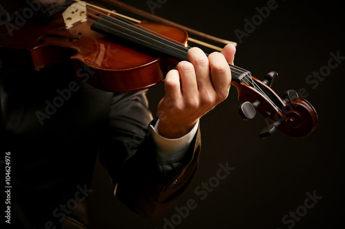 Musician plays violin on black background, close up