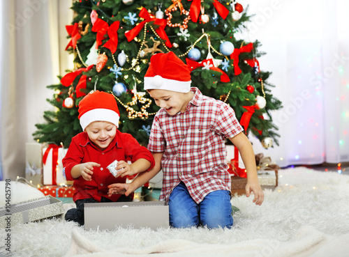 Two cute small brothers opening gifts on Christmas decoration background
