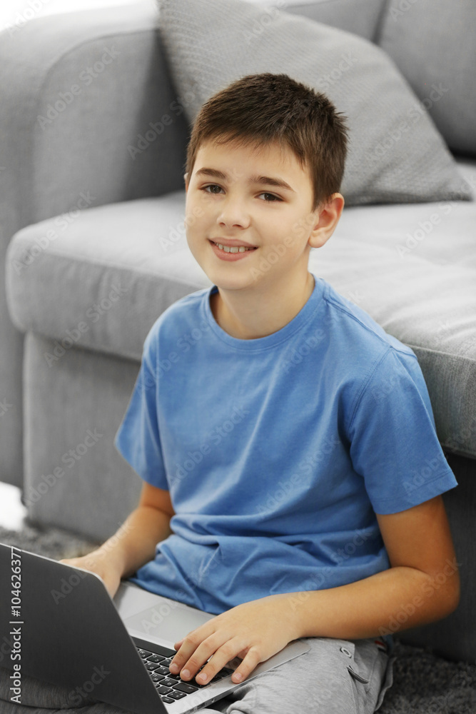 Boy with laptop sitting on a carpet at home Boy with laptop sitting on a carpet at home