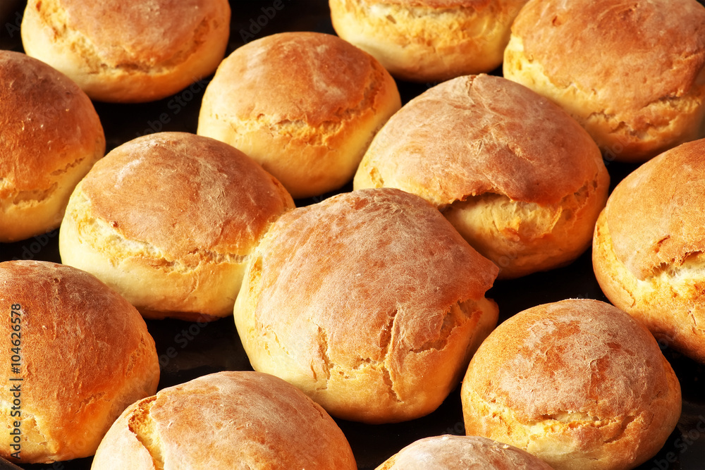 Fresh homemade bread buns on dark baking pan