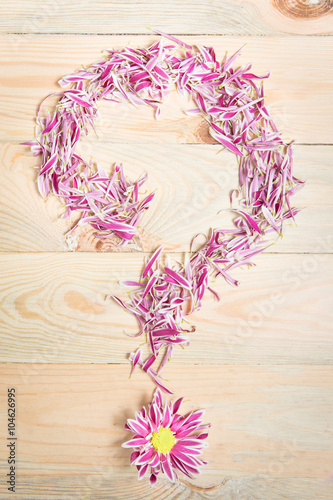 Pink flower petal arrange on wooden background as a question mar