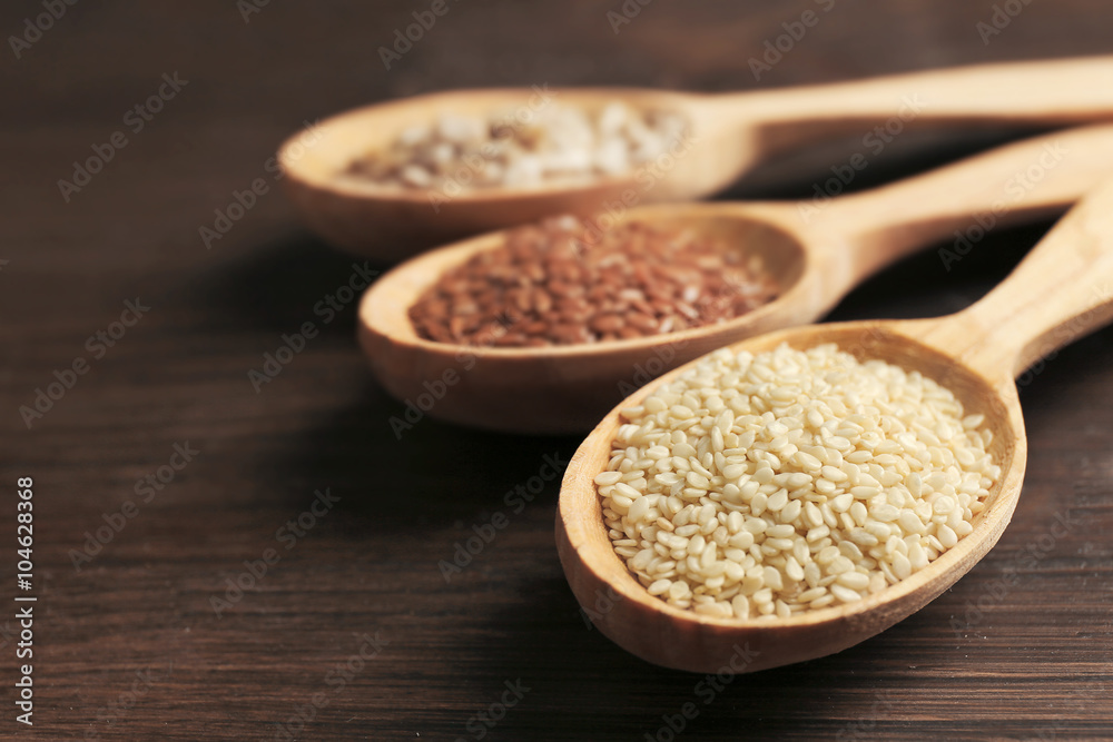 Sesame seeds in wooden spoons on table, closeup Sesame seeds in wooden spoons on table, closeup