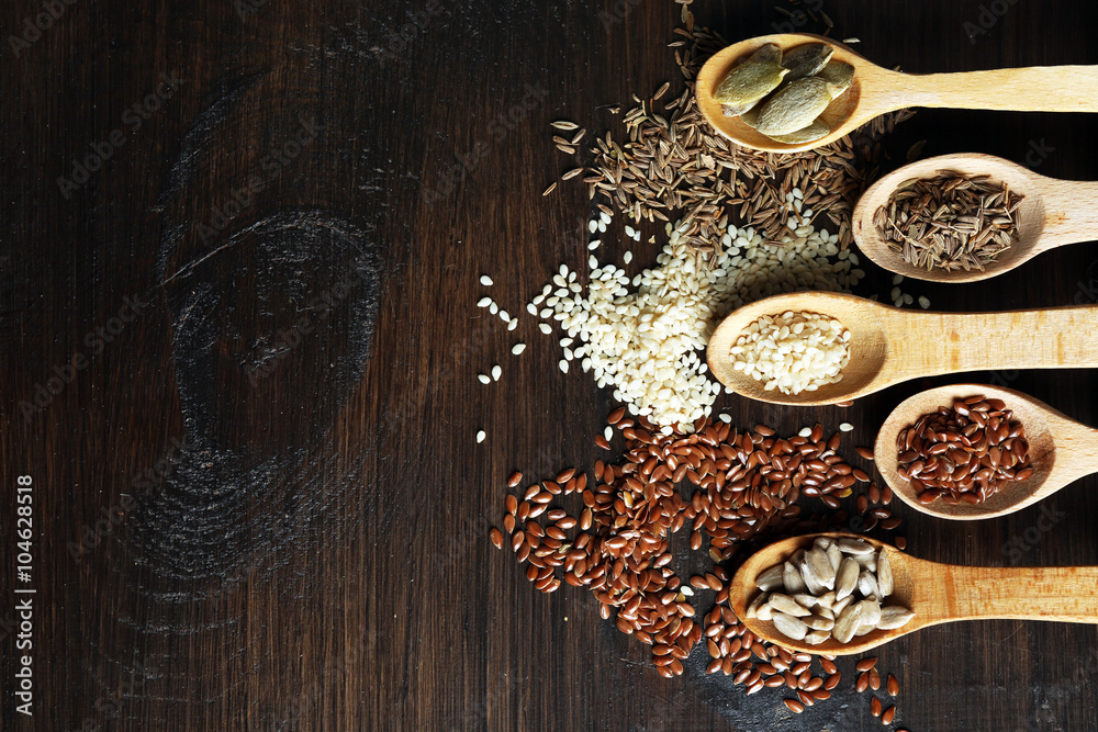 Various seeds in wooden spoons on table, closeup Various seeds in wooden spoons on table, closeup