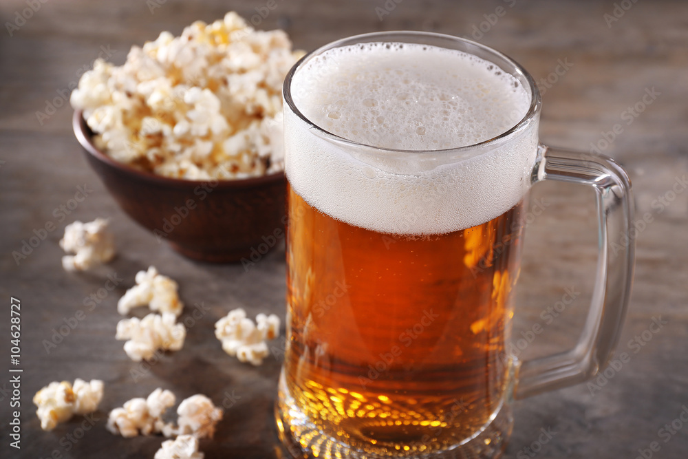 Glass mug of light beer with popcorn on wooden table, close up Glass mug of light beer with popcorn on wooden table, close up