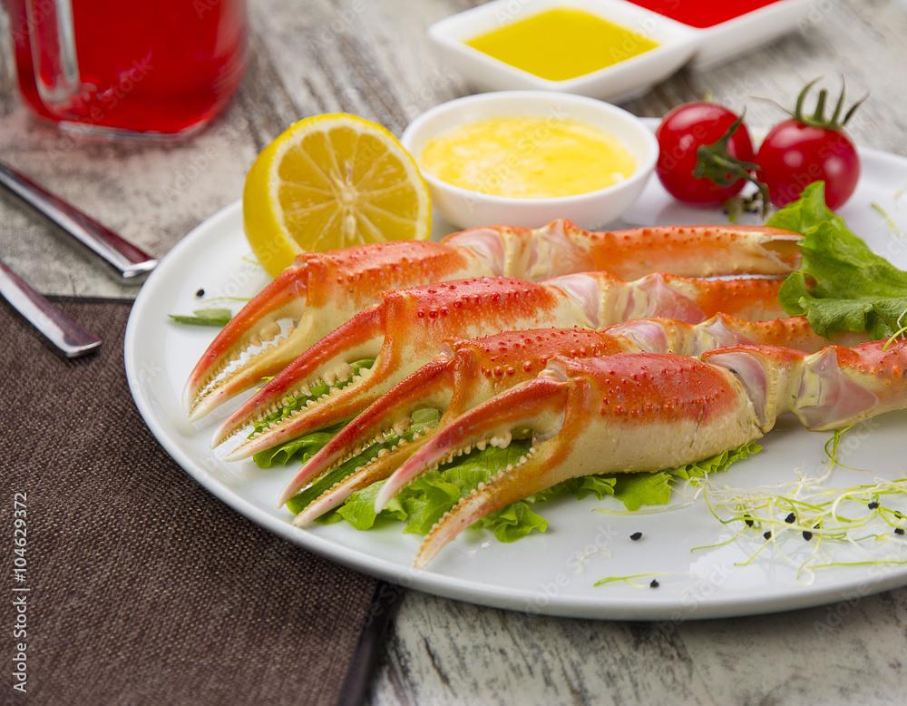 Boiled crab claws with sauce , lemon and cherry tomatoe with tasty drink over wooden background Boiled crab claws with sauce , lemon and cherry tomatoe with tasty drink over wooden background