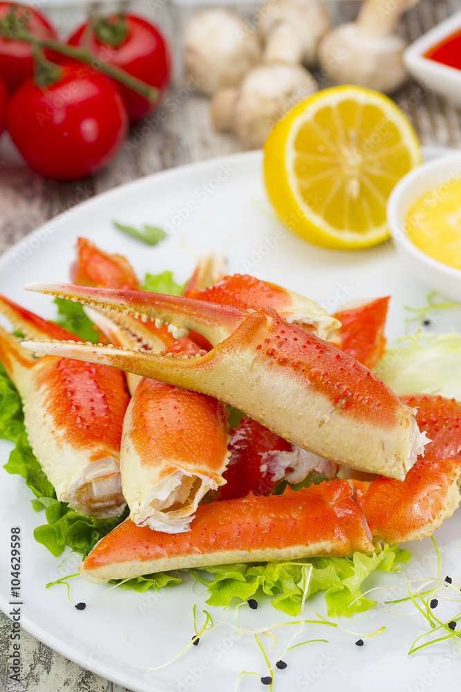 Boiled crab claws with sauce , lemon and cherry tomatoe over wooden background Boiled crab claws with sauce , lemon and cherry tomatoe over wooden background