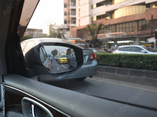 Car on-board driver looking outside to side mirror.