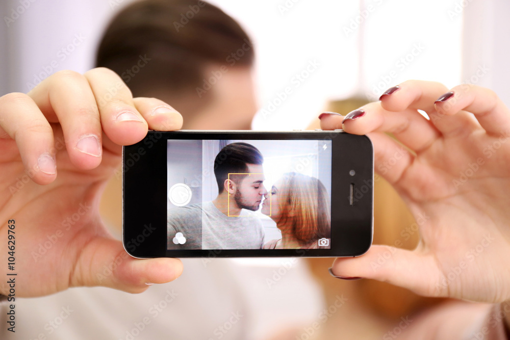 Young couple in love taking photo of their self with mobile phone, close up
