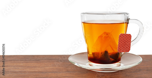 Glass cup with tea bag on wooden table over white background