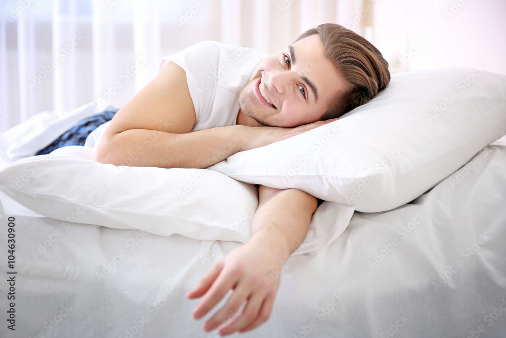 Young smiling man lying in bed at home Young smiling man lying in bed at home