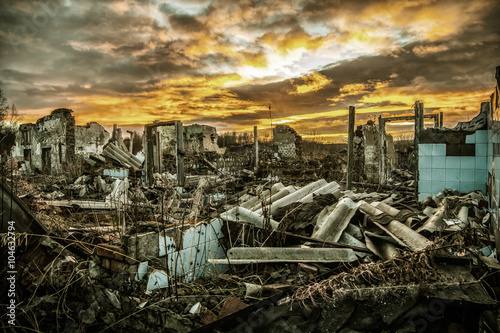 Apocalyptic landscape.The remains of destroyed houses at sunset photo