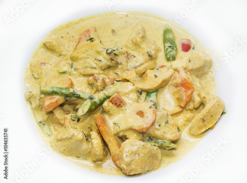chicken curry with vegetables on a white plate in a restaurant