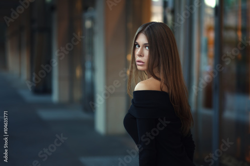 Beautiful brunette young woman in nice black dress. Posing on urban background. Fashion Photo