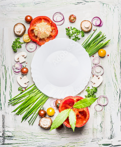Various vegetables and seasoning cooking  ingredients around blank plate on light  rustic wooden background, top view composing. Healthy eating and diet food concept. © VICUSCHKA