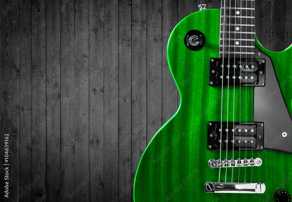 Fototapeta premium Part of the green electric guitar on wooden background. A place for writing of the text.