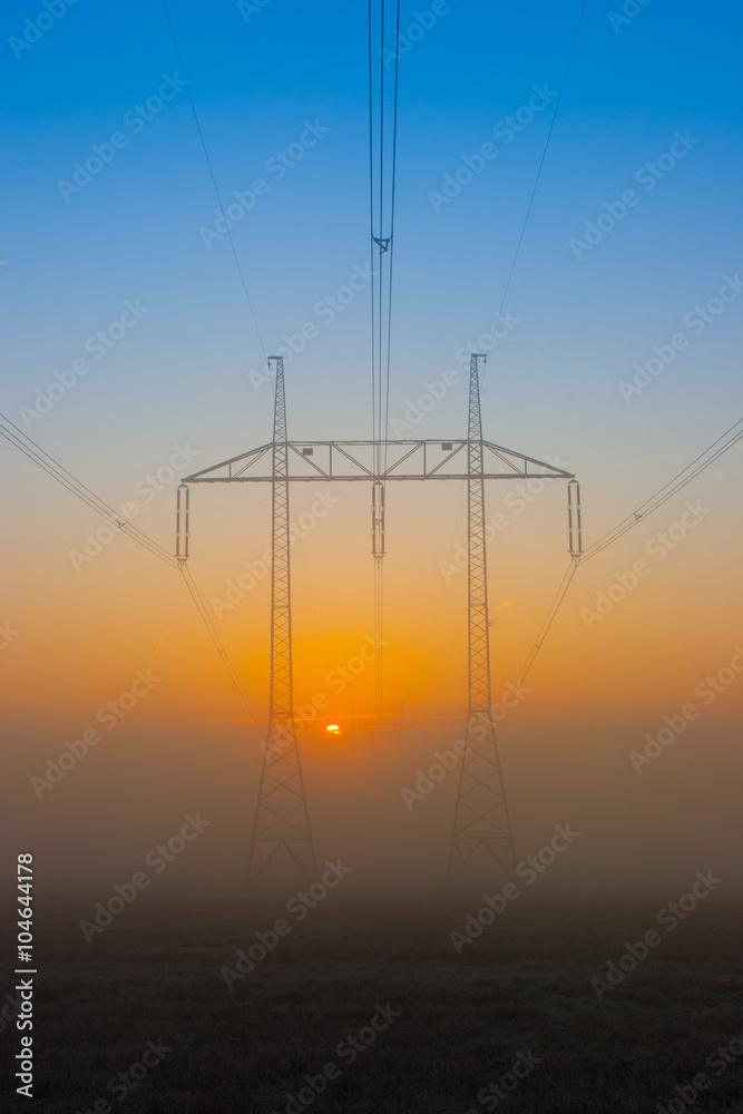Silhouette of high voltage electrical pole structure at sunrise