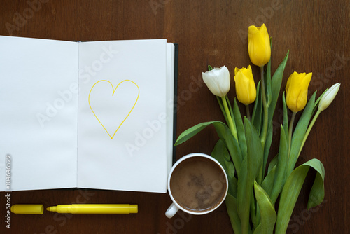 Tulips and heart in a book on a wooden table