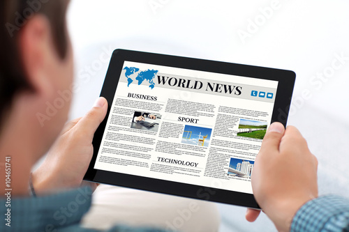 man holding tablet with world news site on a screen