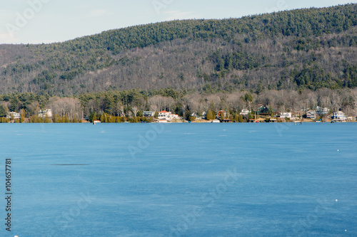 Color DSLR stock image of a frozen Lake George, with lake houses on the shore and Adirondack Mountains in background. Horizontal with copy space for text