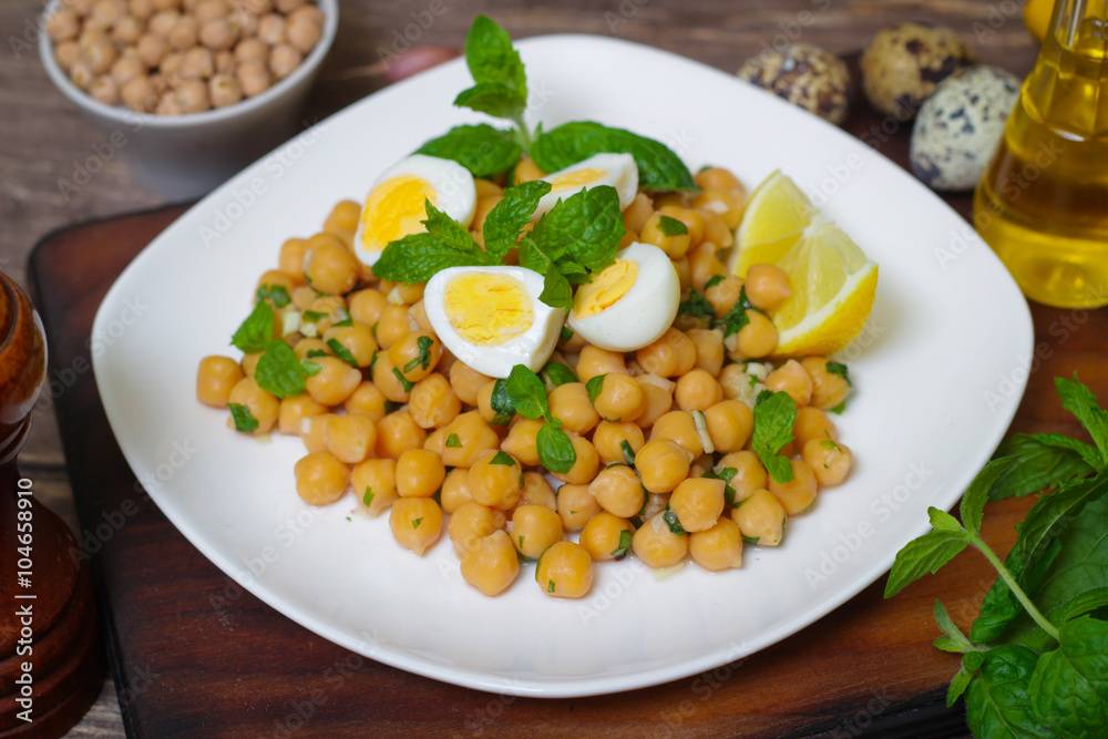 Mediterranean cuisine. Dish of chickpeas with mint, olive oil and lemon sauce on a wooden background Mediterranean cuisine. Dish of chickpeas with mint, olive oil and lemon sauce on a wooden background