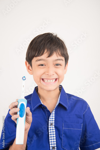 Little boy using electric toothbrushes on white background