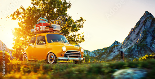 Fototapeta Naklejka Na Ścianę i Meble -  Cute little retro car goes by wonderful countryside road at sunset