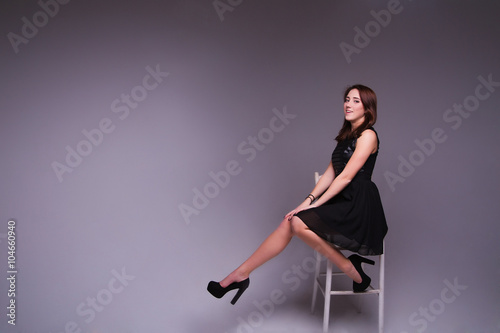 Young elegant woman in black dress, shoes. Sitting and posing i