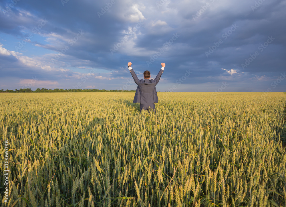 Happy businessman standing on the field to face the sky Happy businessman standing on the field to face the sky
