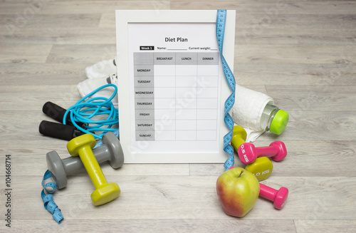 Various sport equipment with diet plan on wooden background
