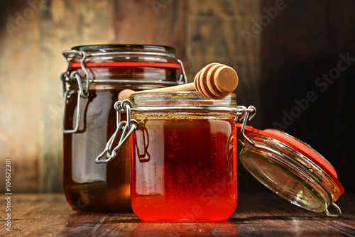 Composition with jars of honey on wooden table