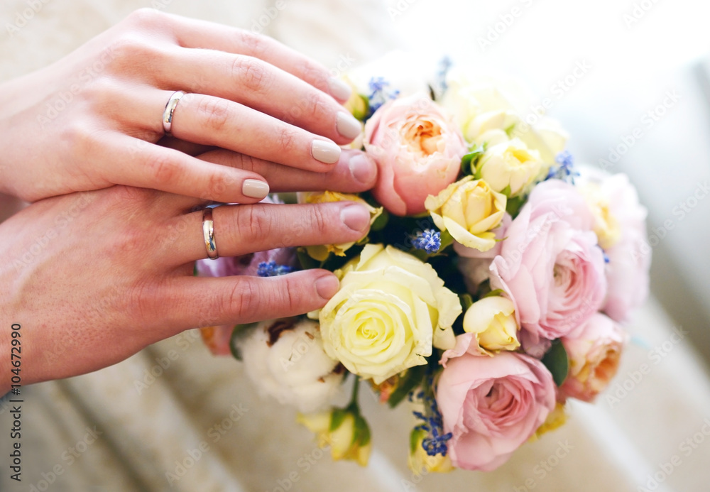 Bride and groom holding hands on a bouquet