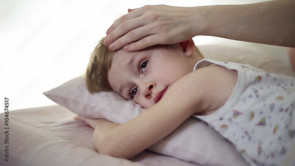 The boy is sick and he has fever and his mom measures his temperature putting a hand to his forehead and using a thermometer
The boy is sick and he has fever and his mom measures his temperature putting a hand to his forehead and using a thermometer