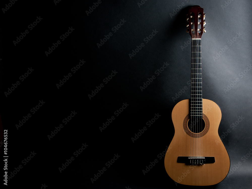 Acoustic guitar on a black background (with copy space) - obrazy, fototapety, plakaty 
