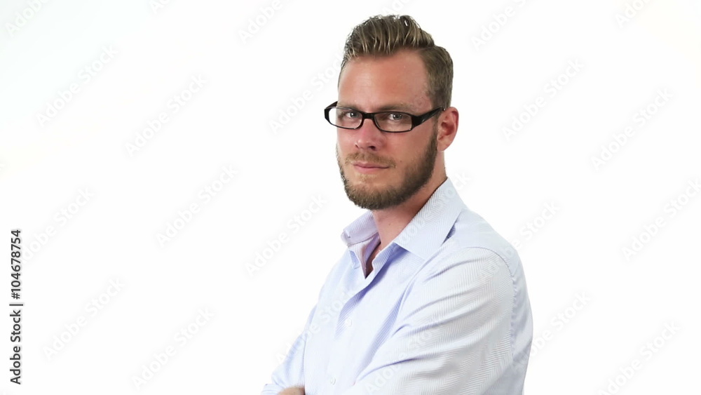 A man in his 20s wearing a light blue shirt with dark glasses, standing in front of a white background looking at camera with a smile on his face. A man in his 20s wearing a light blue shirt with dark glasses, standing in front of a white background looking at camera with a smile on his face.
