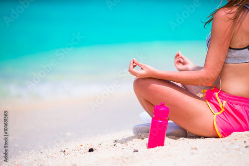 Fitness young woman meditating on the beach