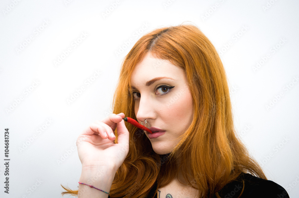 Young redhead woman with red hot chili pepper portrait Young redhead woman with red hot chili pepper portrait