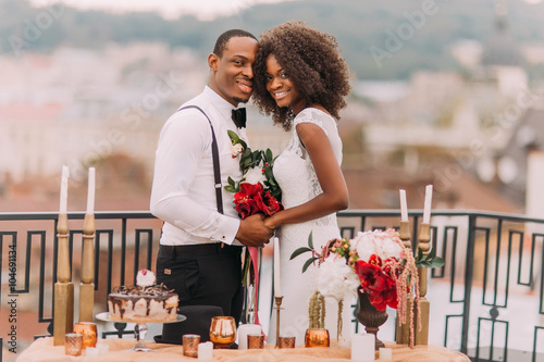 Goregous black wedding couple happily smiling and holding hands photo