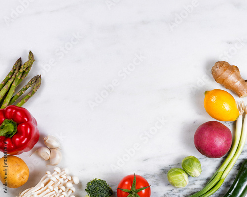 Fresh whole vegetables and fruit displayed on natural marble 