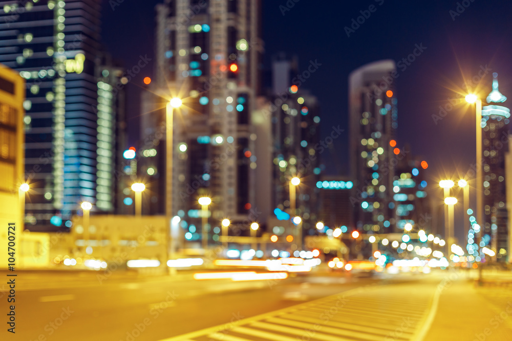 Blurred nighttime cityscape with illuminated modern architecture and street lights. Downtown Dubai, UAE.