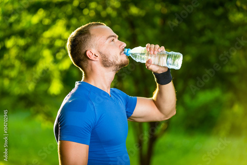 Athletic mature man drinking water from a bottle