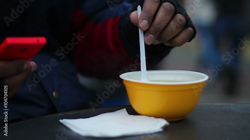 Needy man eating hot soup outdoors in cold windy weather, manual worker's lunch photo