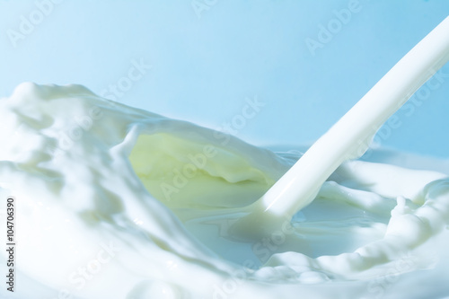 splash of milk, pouring jet stream of milk on a light blue background 