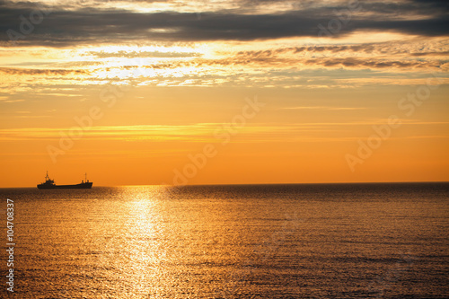 Cargo ship sailing on sunrise near the beach