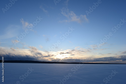 Sunset on a snowy winter lake in a cloudless blue sky