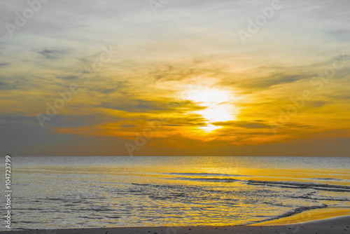 Sun sets over horizon of ocean. Sky  water and shore in the even
