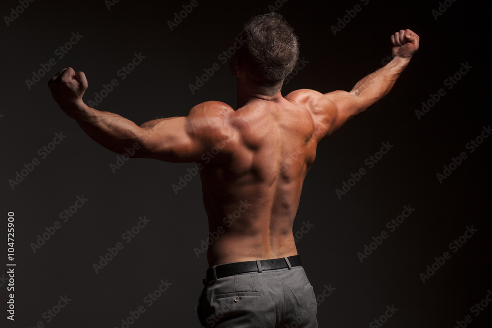 back view of naked muscular man in pants on gray