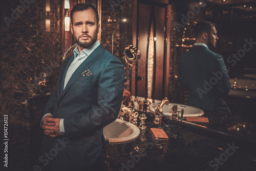 Confident well-dressed man in luxury bathroom interior.