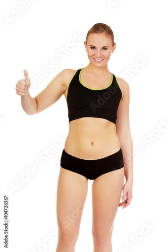 Young athletic woman showing thumb up